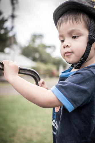 Cute mixed race boy pumps water from an antique water pump - Australian Stock Image