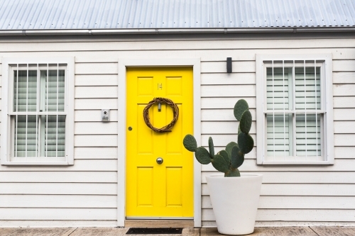 Cute white weatherboard cottage with yellow door and cactus in paddington, sydney - Australian Stock Image