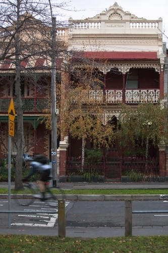 Cyclist riding down a street in city inner suburbs. - Australian Stock Image