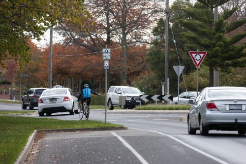cyclist signaling while turning right in a roundabout - Australian Stock Image
