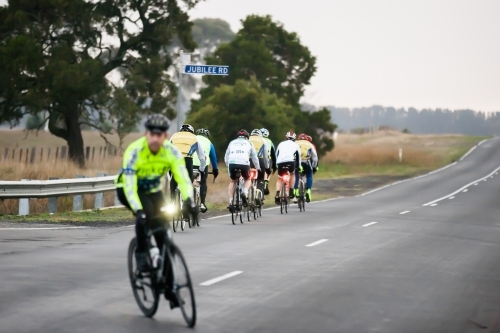 Cyclist turing at intersection after another group has passed - Australian Stock Image