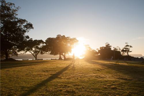 Cyclist walking bike across the sunrise at a park - Australian Stock Image