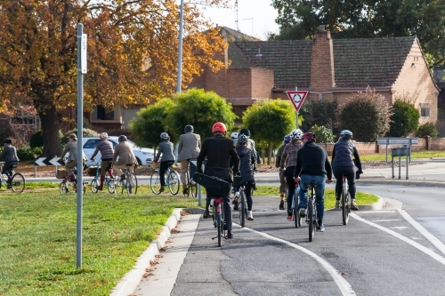 Cyclists on a Tweed Ride approaching a roundabout in a city - Australian Stock Image