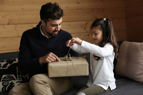 Dad and daughter opening present in lounge room