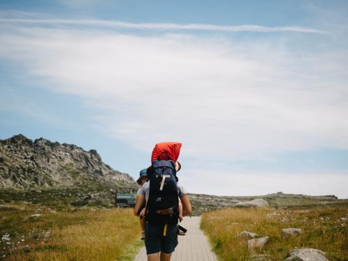 Dad carrying two kids walking along path in the mountains - Australian Stock Image