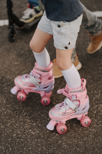 Dad guiding daughter on roller blades on the street. - Australian Stock Image