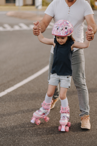 Dad helping daughter find balance in roller skates - Australian Stock Image