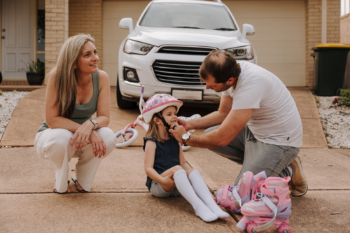 Dad helping daughter fix her helmet while mum sits on the side.. - Australian Stock Image