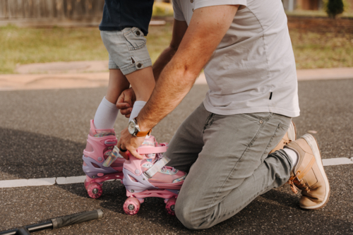 Dad helping daughter get into her roller skates - Australian Stock Image