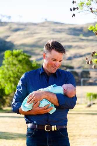 Dad holding his newborn baby daughter bonding and smiling - Australian Stock Image