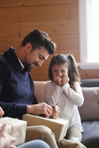 Dad opening present with daughter looking on - Australian Stock Image