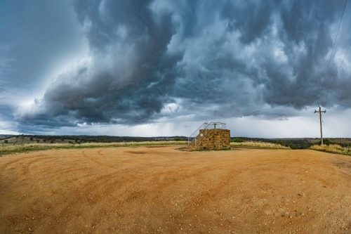 Dark cloud formations over a raised stone lookout platform - Australian Stock Image