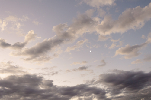 Dark Purple Cloudy sky with small crescent moon - Australian Stock Image