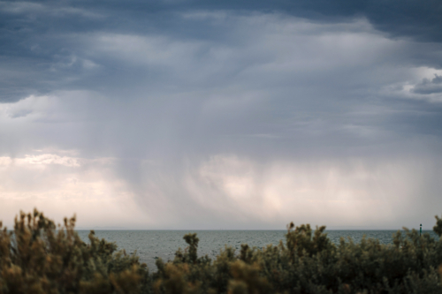 Dark rain clouds with streaks falling above coastal horizon - Australian Stock Image