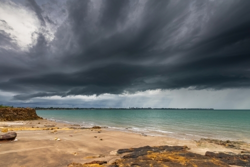 Dark storm clouds over the ocean and Darwin city