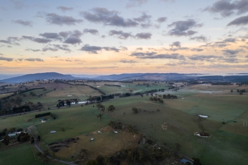 Dawn colours in the sky while the green countryside is shown below in rural Australia - Australian Stock Image