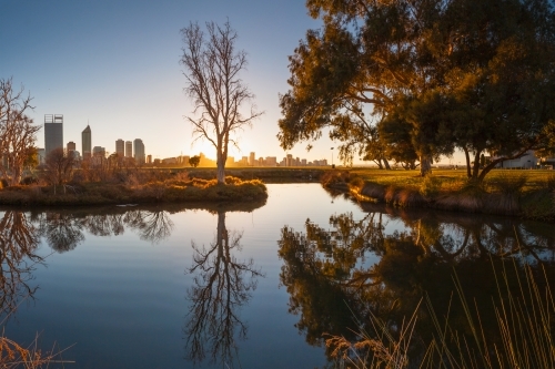 Dawn over an inner city lake with reflections of nearby trees - Australian Stock Image
