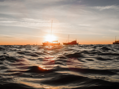 Dawn over ocean with boats in background - Australian Stock Image