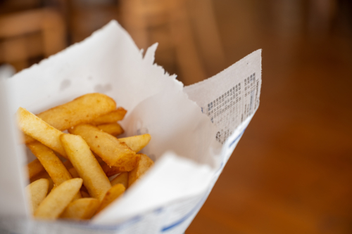 Deep fried chips in a wire basket lined with wax paper - Australian Stock Image
