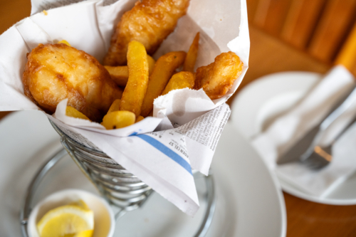 Deep fried fish and chips in a wire basket lined with wax paper - Australian Stock Image