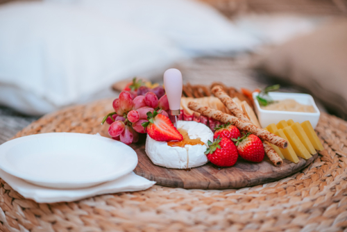 Delicious cheese platter featuring fresh fruits and snacks for a casual outdoor gathering - Australian Stock Image