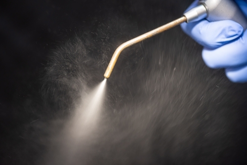 Dental air water syringe with water spray on black background - Australian Stock Image