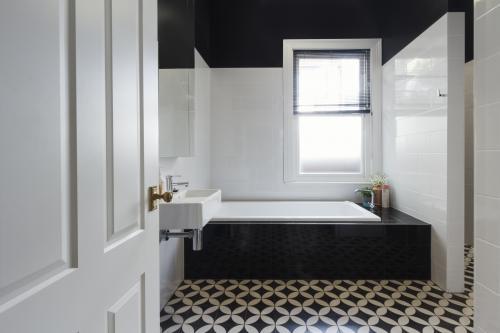 Designer bathroom renovation with monochrome moroccan floor tiles and black bath hob - Australian Stock Image