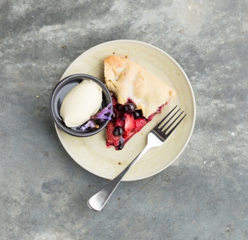 Dessert of strawberry and blueberry tart with cream on a concrete table