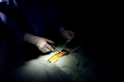 Detail of a surgeon performing surgery in a hospital operating theatre - Australian Stock Image