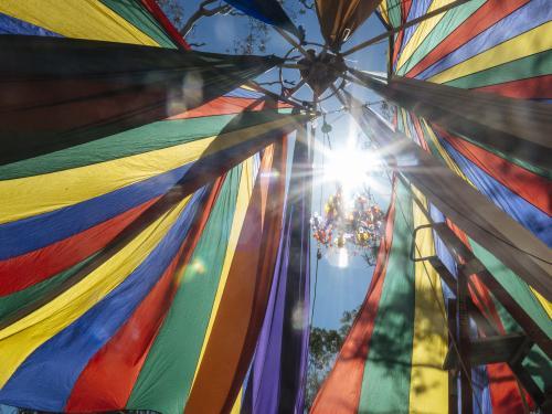 Detail of Rainbow Coloured Parachute Material at Festival with Sun