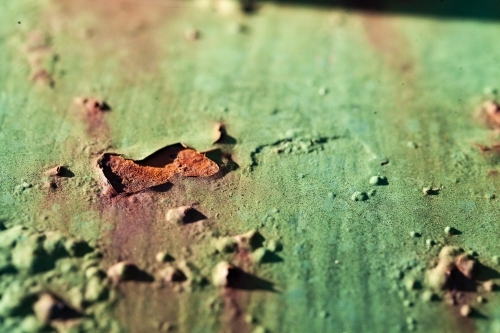 Detail of rusted holes in painted metal surface