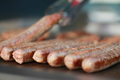 Detail row of BBQ sausages cooking