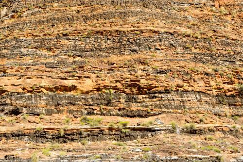 Detail shot of heavily textured and layered rock with yellow and orange colours - Australian Stock Image
