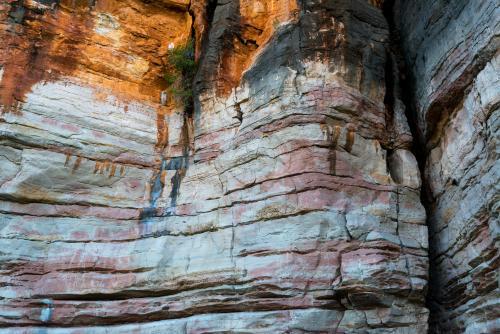 Detail shot of layered and patterned rock with orange, pink and yellow colours - Australian Stock Image