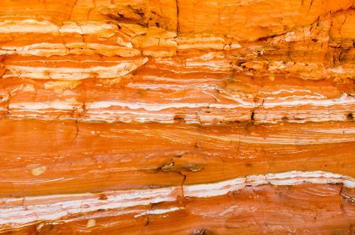 Detail shot of layered and patterned rock with orange, pink and yellow colours - Australian Stock Image