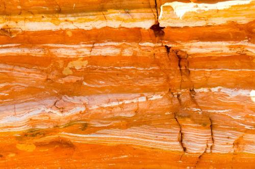Detail shot of layered and patterned rock with orange, pink and yellow colours - Australian Stock Image