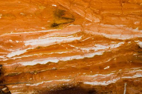 Detail shot of layered and patterned rock with orange, pink and yellow colours - Australian Stock Image