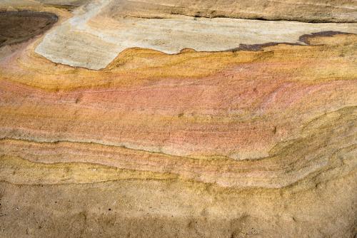 Detail shot of layered pink, yellow and orange sedimentary rock