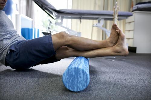 Detail shot of male patient using a foam roller in a physio studio - Australian Stock Image