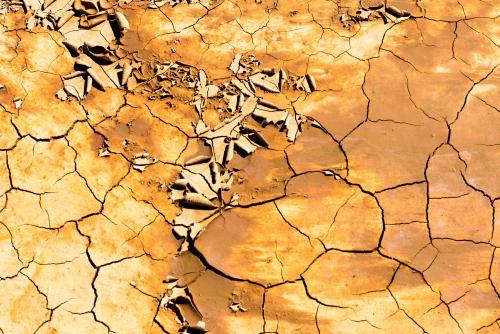 Detail shot of mottled orange and yellow mud and clay that is cracked and peeling - Australian Stock Image