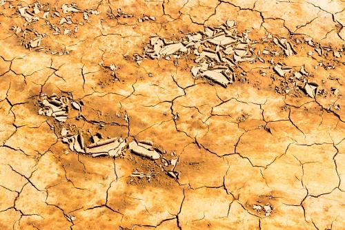 Detail shot of mottled orange and yellow mud and clay that is cracked and peeling - Australian Stock Image