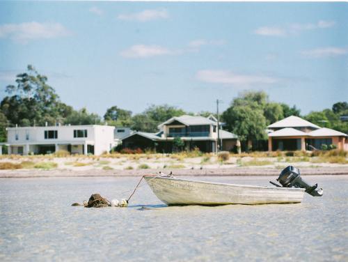 Dinghy moored in water with houses in background