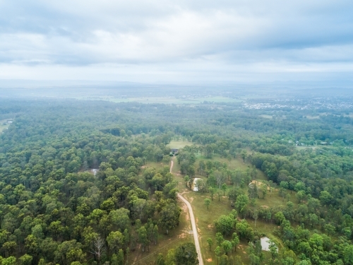 Dirt driveway into rural property covered in trees on misty overcast morning - Australian Stock Image