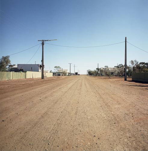 Dirt road in remote town with houses and power lines