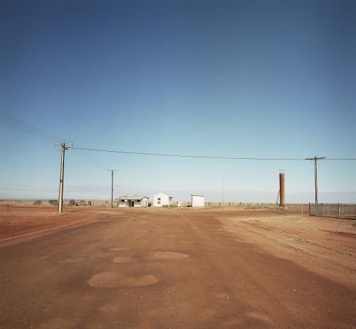 Dirt road in remote town with houses and power lines - Australian Stock Image