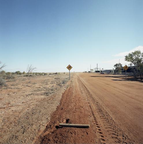 Dirt road in remote town with people crossing sign