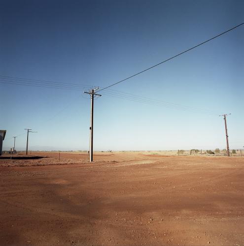 Dirt road in remote town with power lines - Australian Stock Image