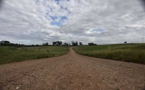 Dirt road leading into horizon, grass on both sides - Australian Stock Image