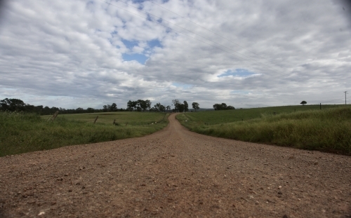 Dirt road leading into horizon, grass on both sides