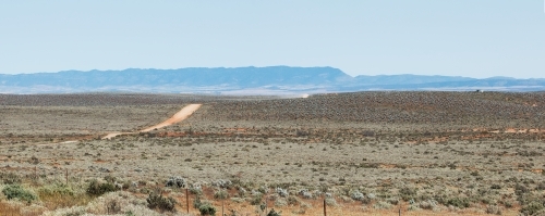 dirt road through plains going towards hills